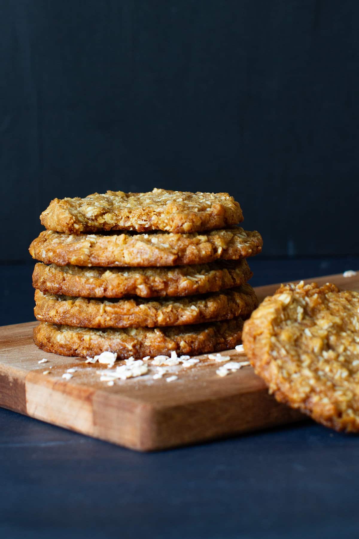 A stack of Anzac biscuits on a wooden board.