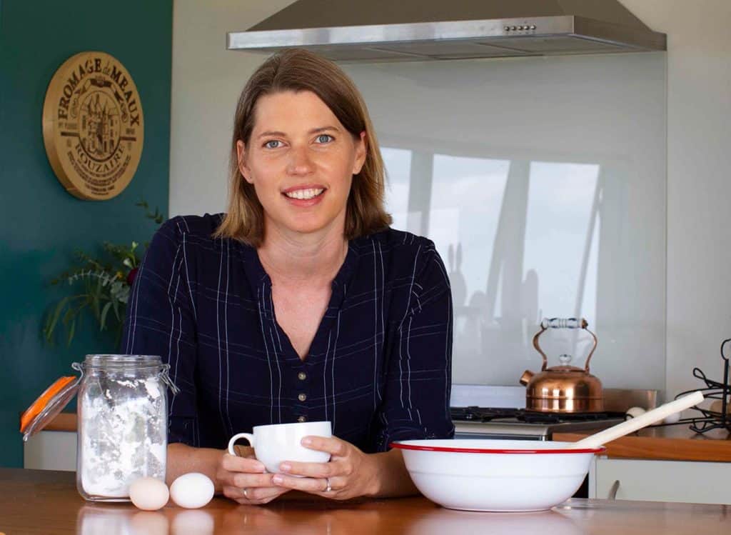 Caro in her country kitchen holding a white tea cup