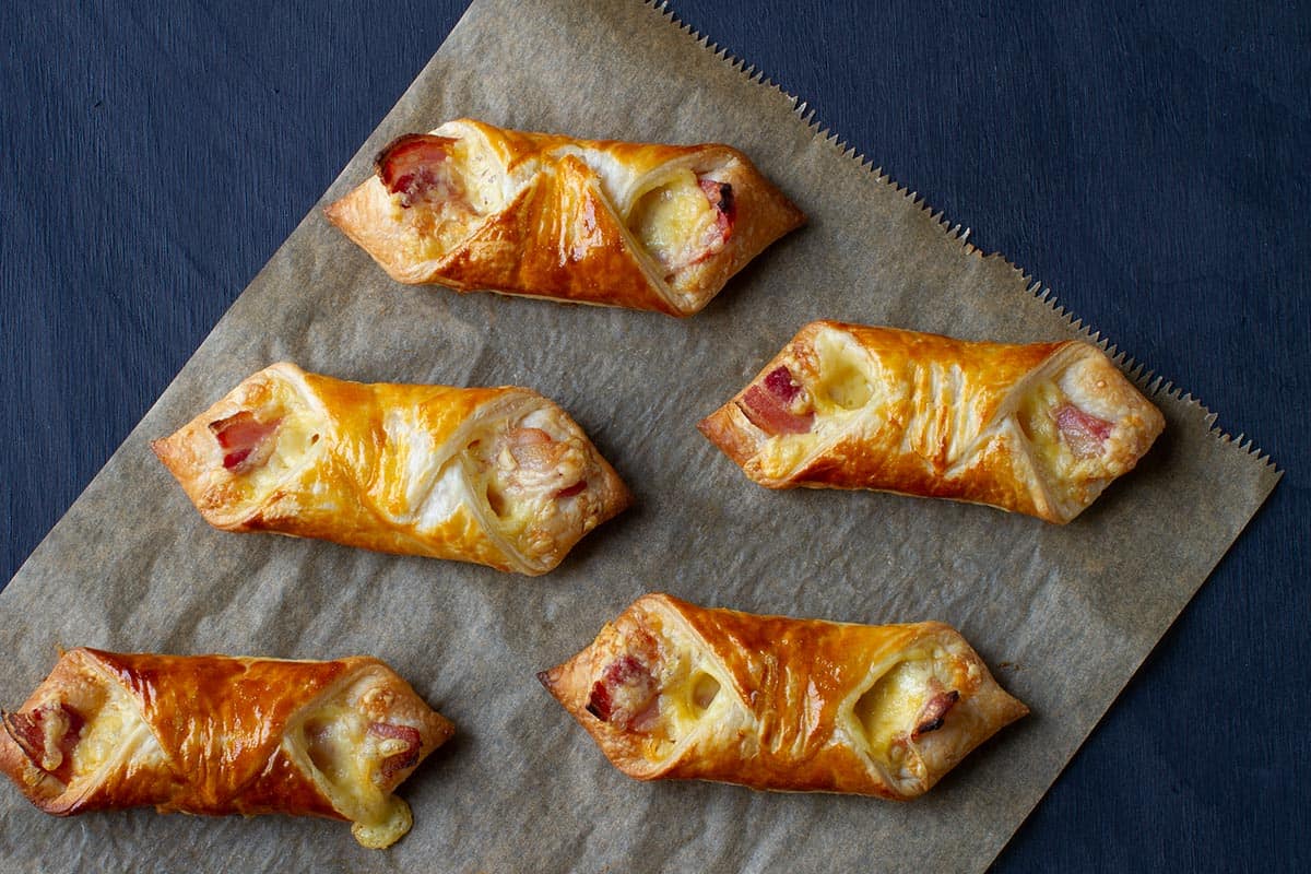 Five cheese and bacon turnovers on a piece of baking paper