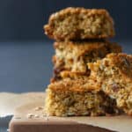 Five chewy granola bars on baking paper and a wooden board.