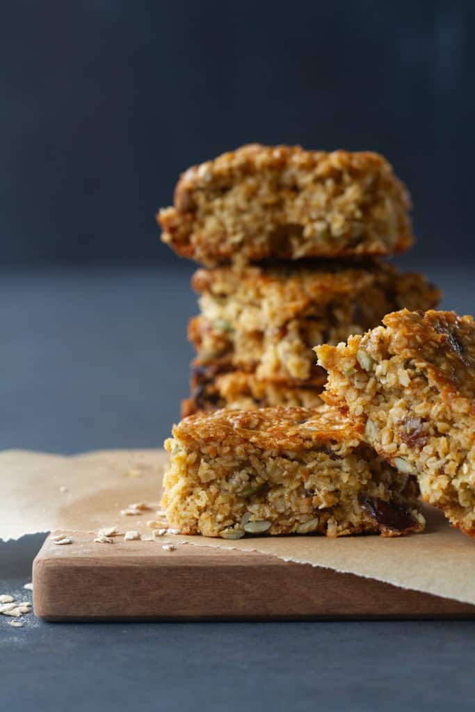 Five nut-free muesli bars on baking paper and a wooden board.