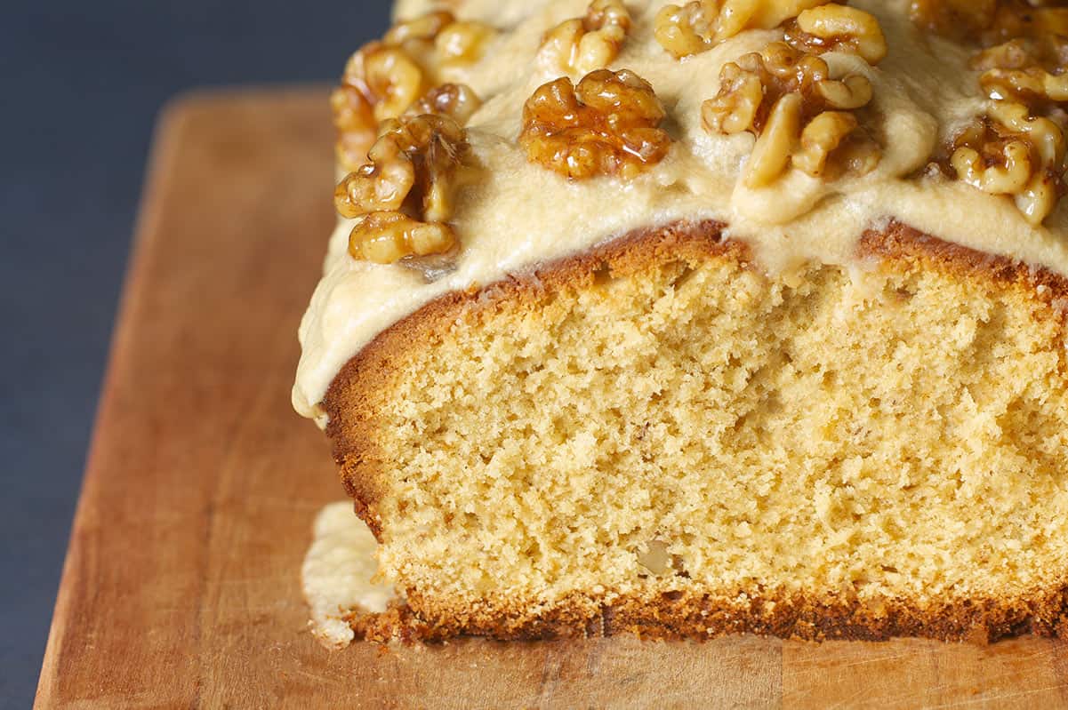 Close-up of a coffee and walnut loaf cake on a wooden board.