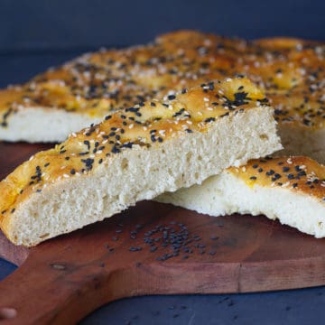 Small slices of Turkish pide bread on a round wooden board.