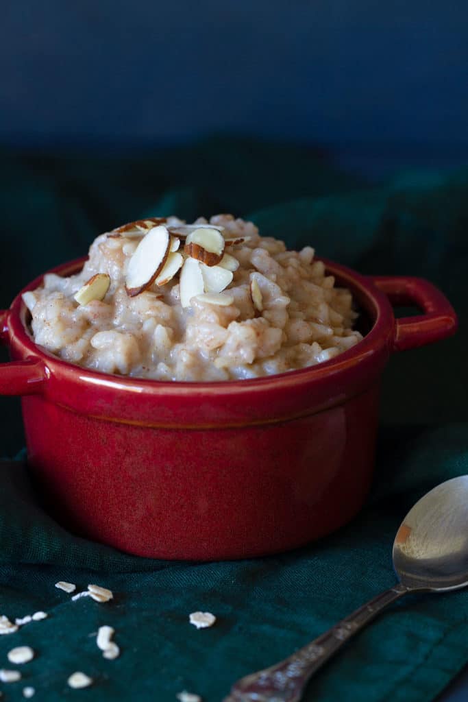A red bowl of creamy rice pudding on a dark background.