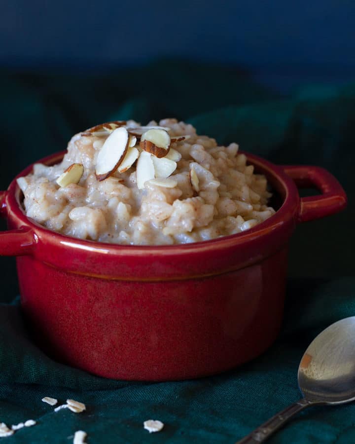 A red bowl of creamy rice pudding on a dark background.