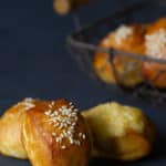 Three pretzel bites with different toppings. A basket of more bites is in the background blurred out.