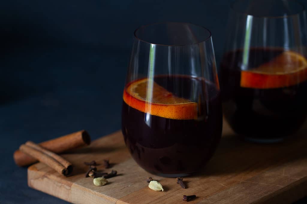 Two glasses of non-alcoholic mulled wine with orange slices in it. Spices as garnish.