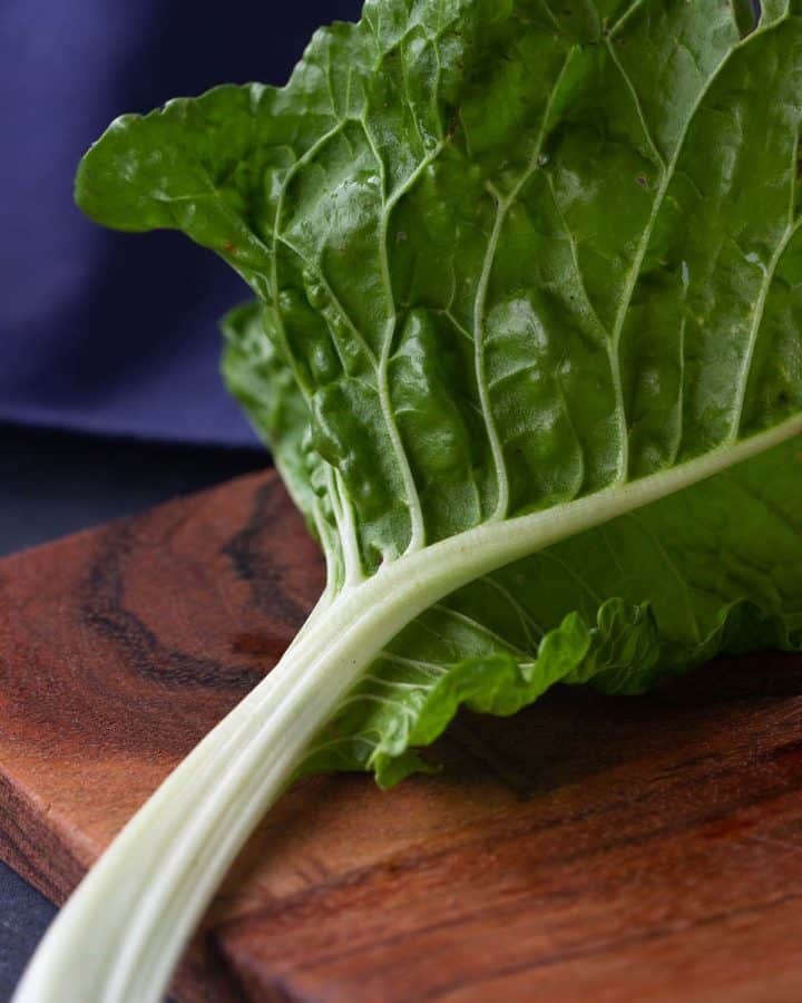A stem of silverbeet on a wooden board.