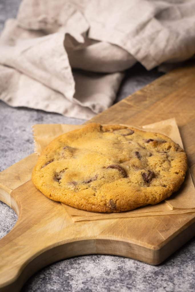 A chocolate chip cookie in a wooden board.
