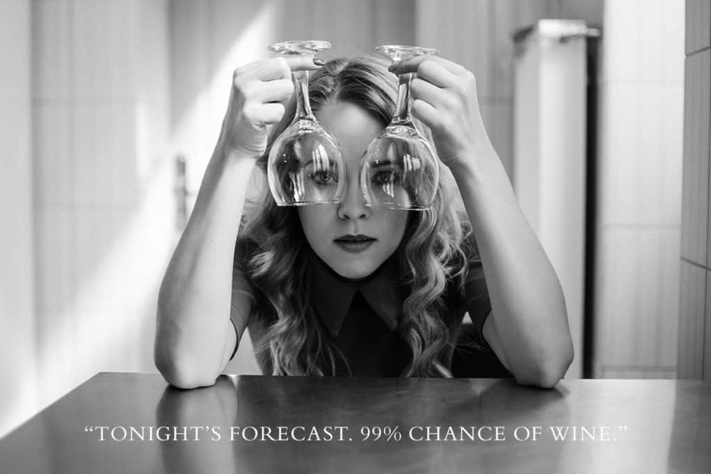 A woman looking through two wine glasses.