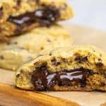 Two giant chocolate stuffed cookies on a wooden board.