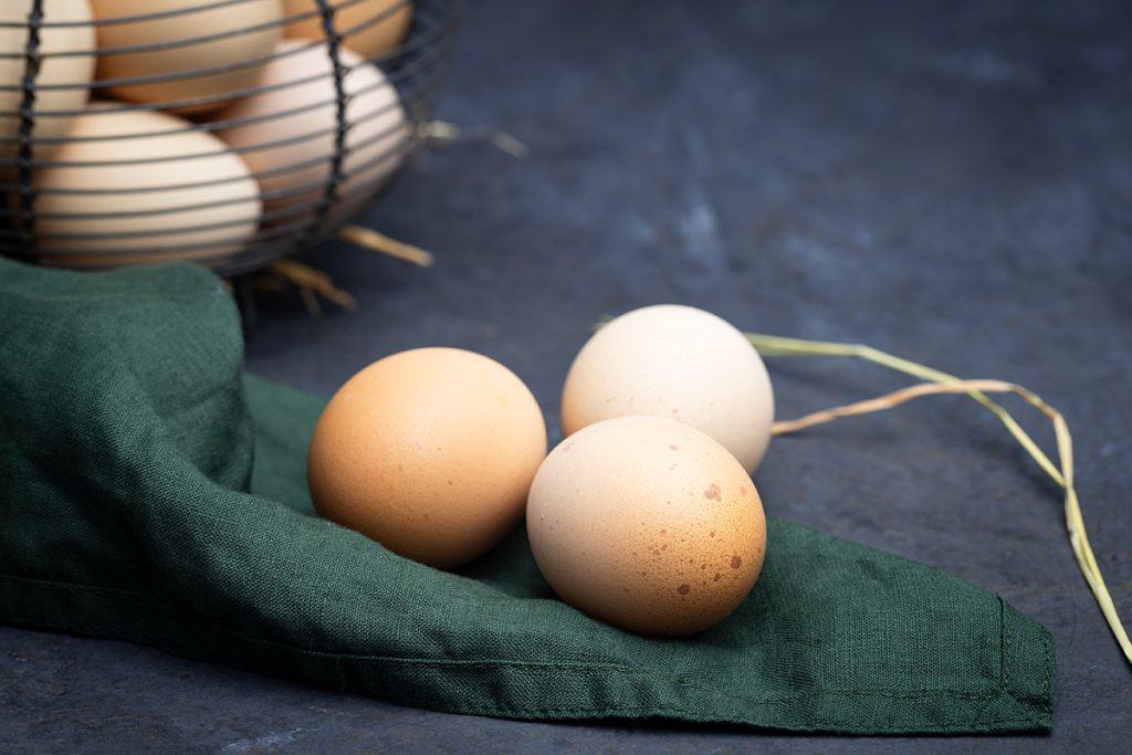 Three farm fresh eggs on a green napkin.
