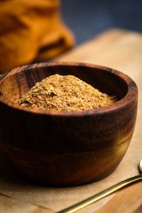 Homemade burrito spice mix in a wooden bowl on a wooden board.