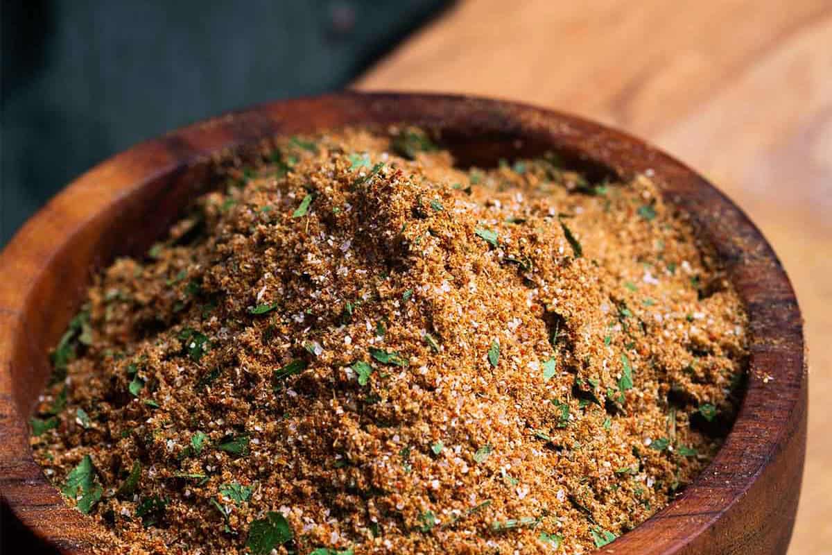 Chermoula spice blend in a wooden bowl which sits on a wooden board.