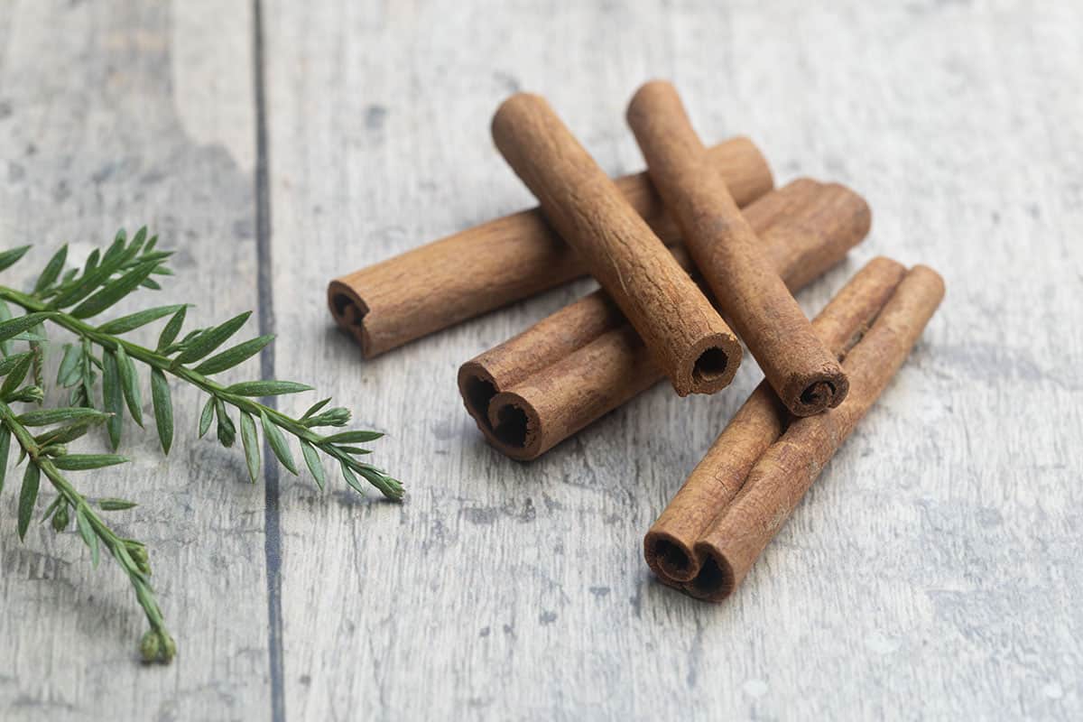 Five cinnamon quills on a wooden board.