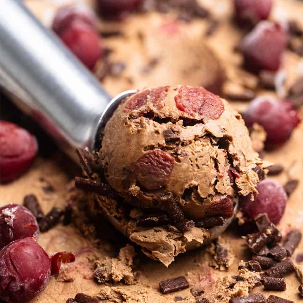 A close-up of condensed milk chocolate cherry ice cream being scooped.