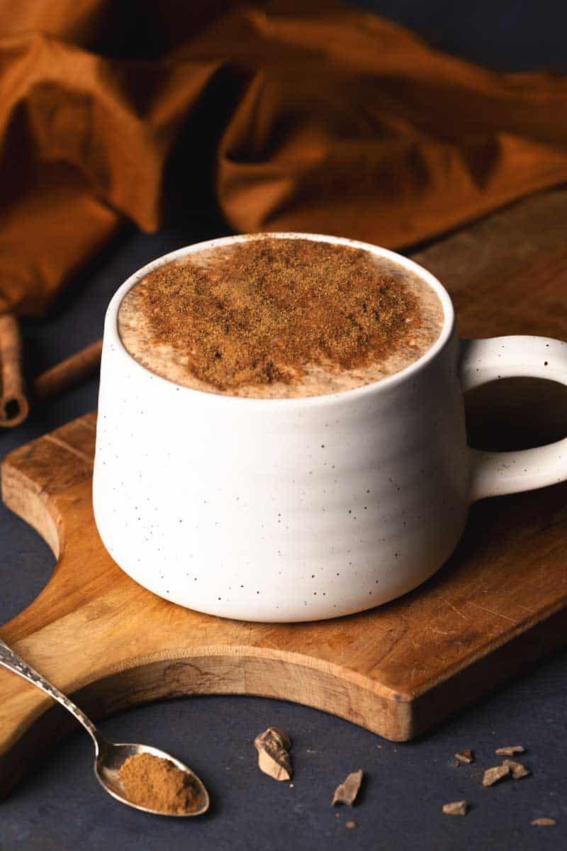 A mug of pumpkin spiced hot chocolate on a wooden board.