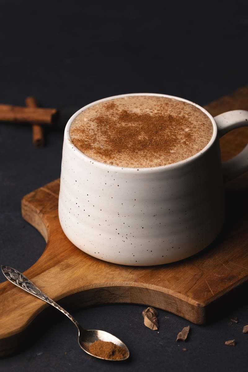 A mug of pumpkin spiced hot chocolate on a wooden board.