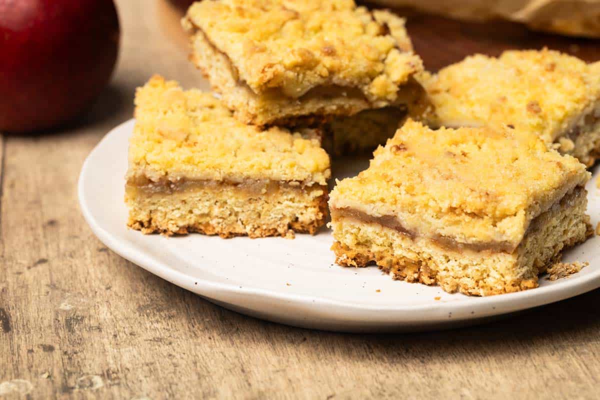 Apple bars on a white plate next to red apples.