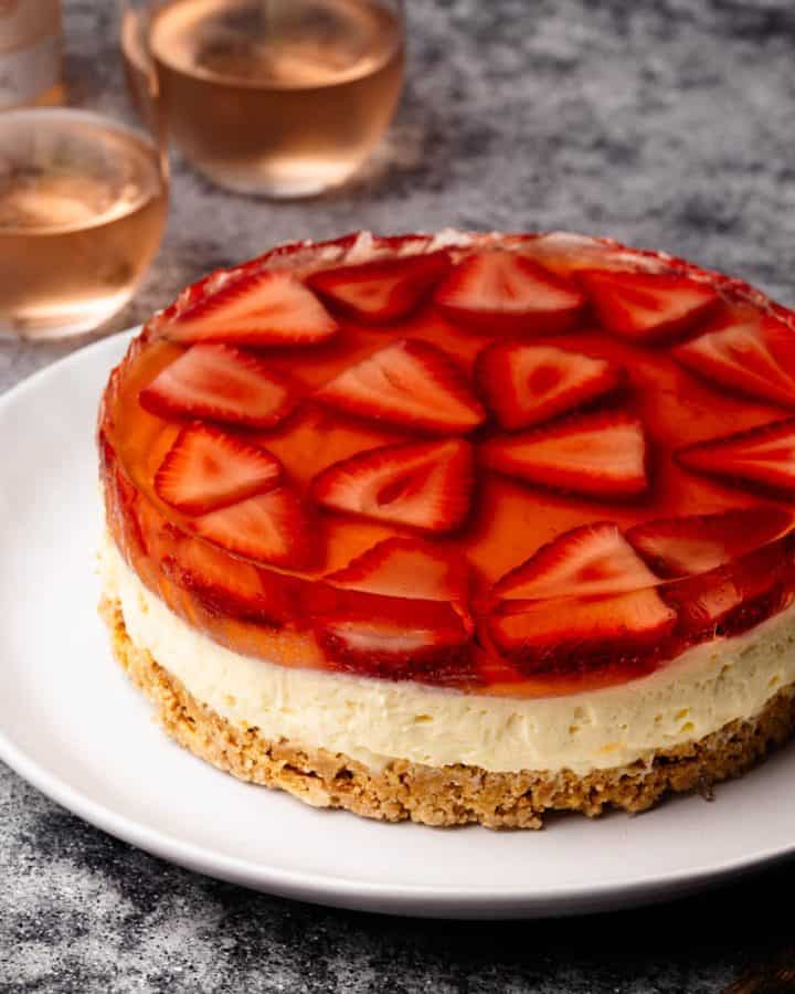 A Strawberry Rosé Cake on a white plate next to Rosé glasses.