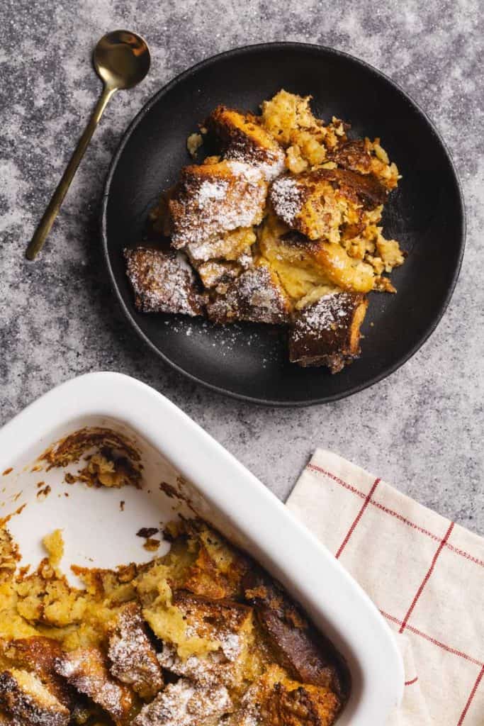 Baked French toast with brioche on a plate next to the casserole dish.