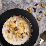A bowl of milk soup with pasta on a black plate.