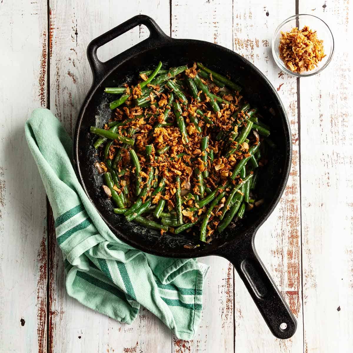 Green bean casserole cooked in a cast iron skillet served as a side.