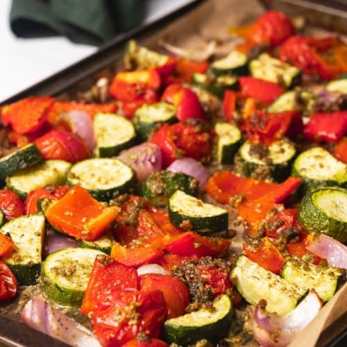 A large tray of pesto roasted vegetables next to a green napkin.