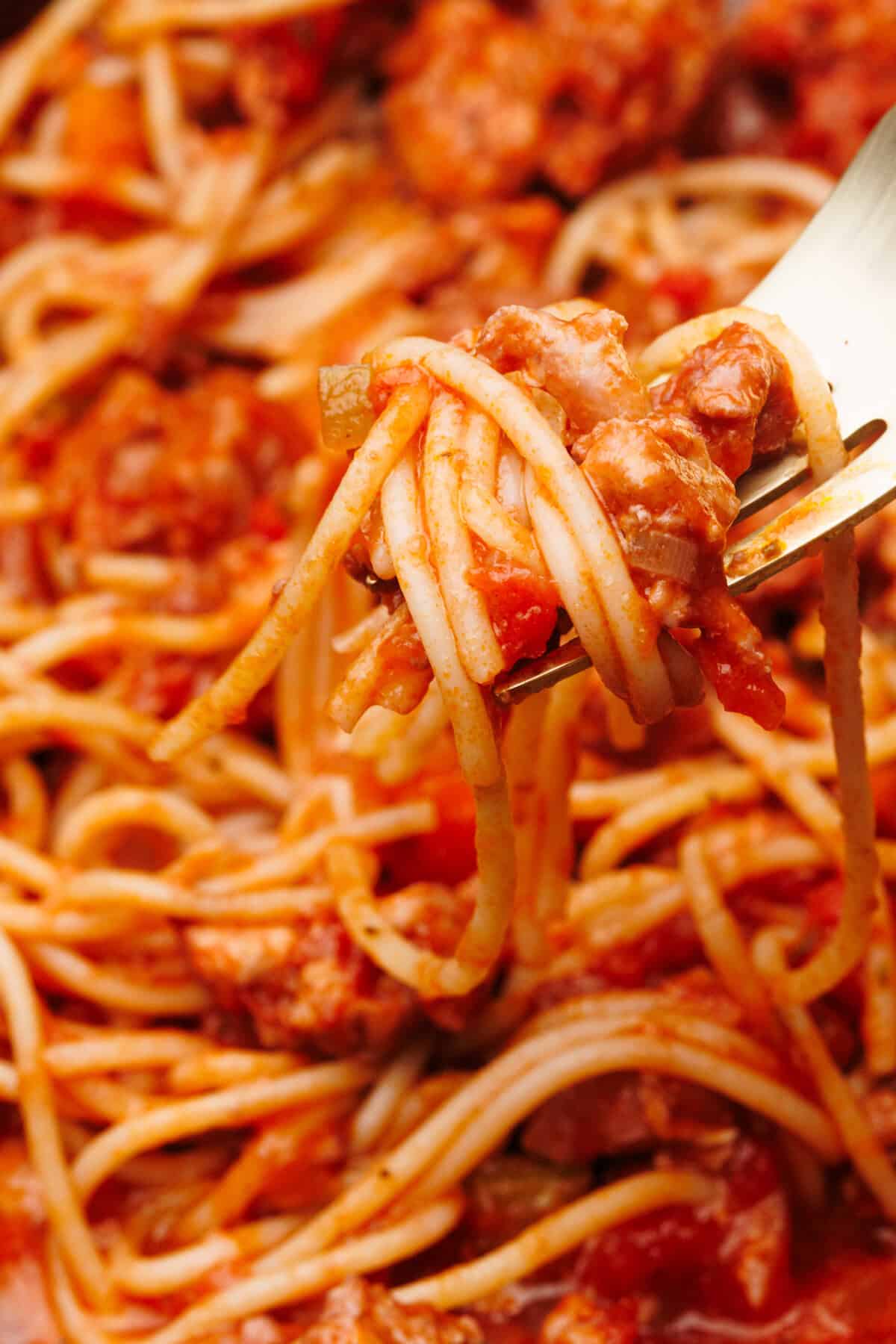 Close-up of a fork with chicken spaghetti bolognese on it.