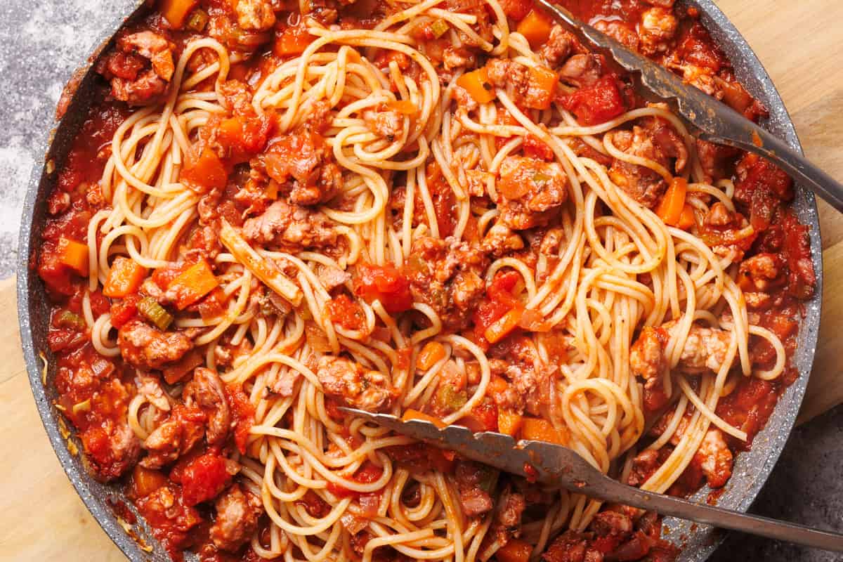 A large pan with chicken spaghetti bolognese, ready to be served.