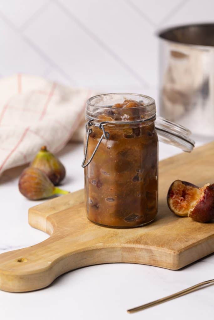 Fresh fig chutney in a glass jar next to a large pot.