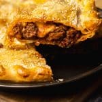 A slice of ground lamb pie being lifted from the pie dish.