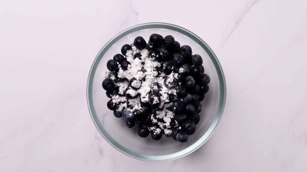 Blueberries in a bowl with sugar and lemon juice.
