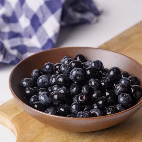 Macerated blueberries in a brown bowl which is sitting o