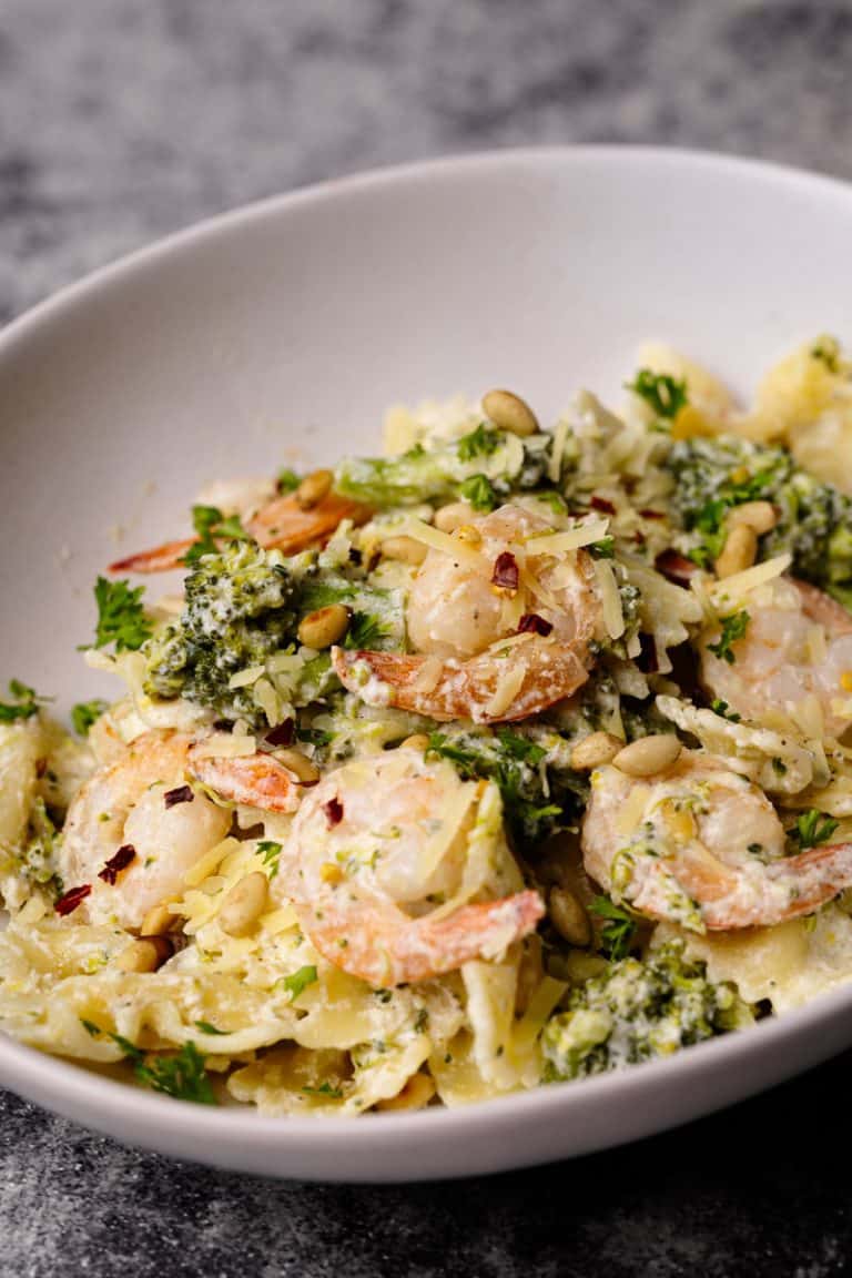A white pasta bowl filled with shrimp broccoli pasta.