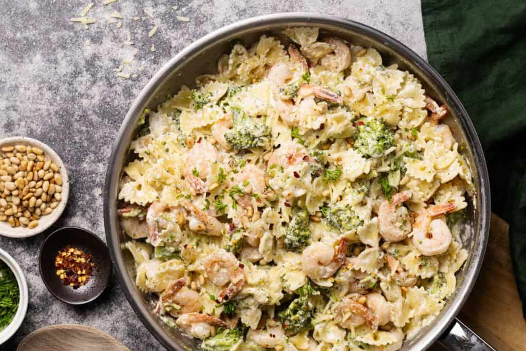 A large pan filled with shrimp broccoli pasta.