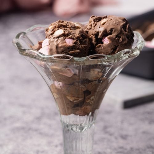 Three scoops of chocolate marshmallow ice cream in a dessert glass.
