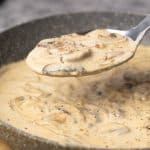 Mushroom sour cream sauce in a grey pan being scooped out.