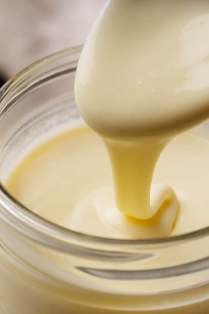 Close-up of condensed milk being scooped out of a jar.