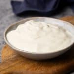 Yogurt in a small bowl on a wooden board.