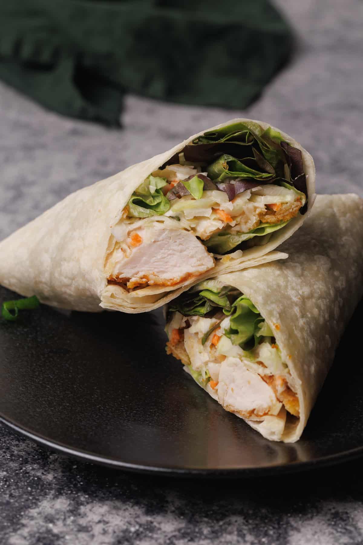 A chicken wrap on a black plate.