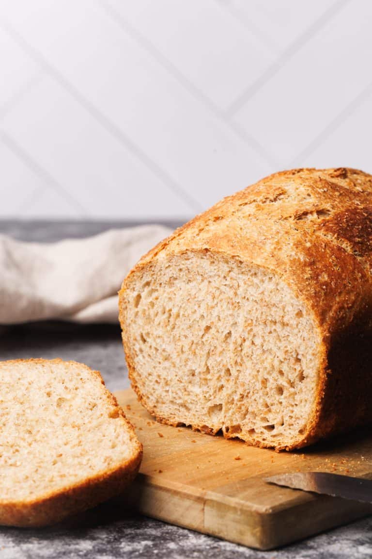 A loaf of cold fermented bread cut open on a wooden board.