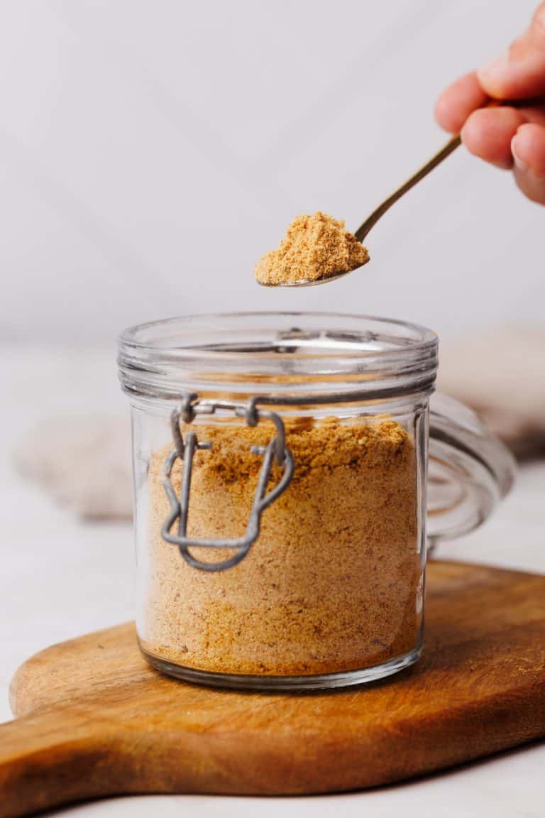 Milk powder being scooped out of a glass container.