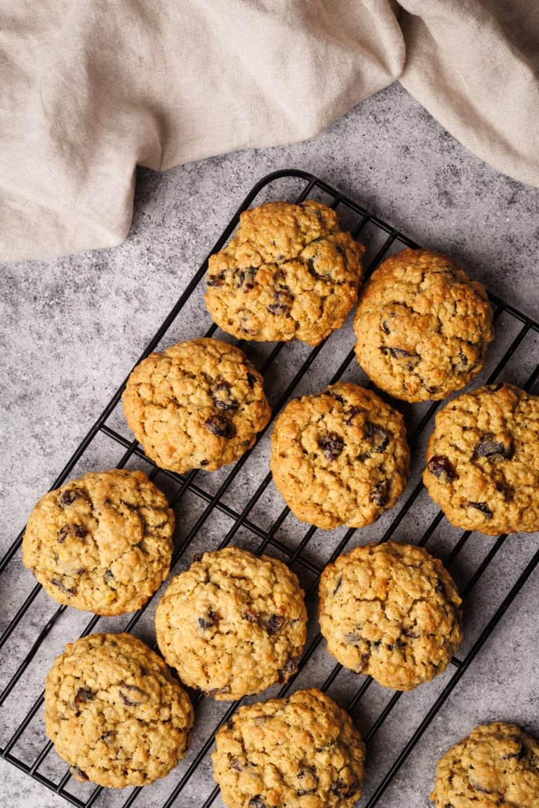 Oatmeal cookies on a cooling rack next to linen towel.