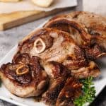 Pan-fried lamb shoulder chops on a white plate.