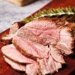 Lamb roast sliced up on a wooden board.