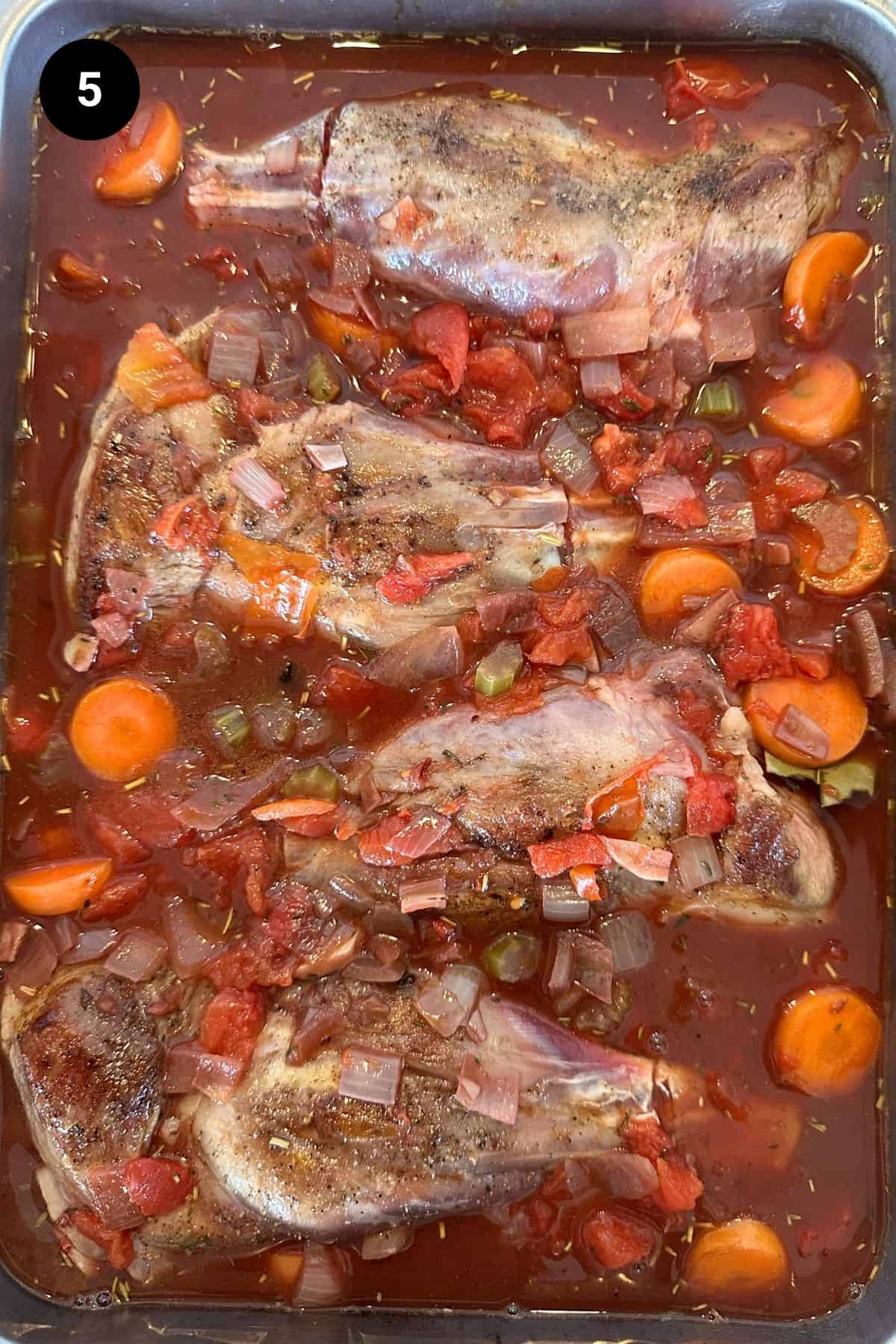 Uncooked lamb shanks in a casserole dish.