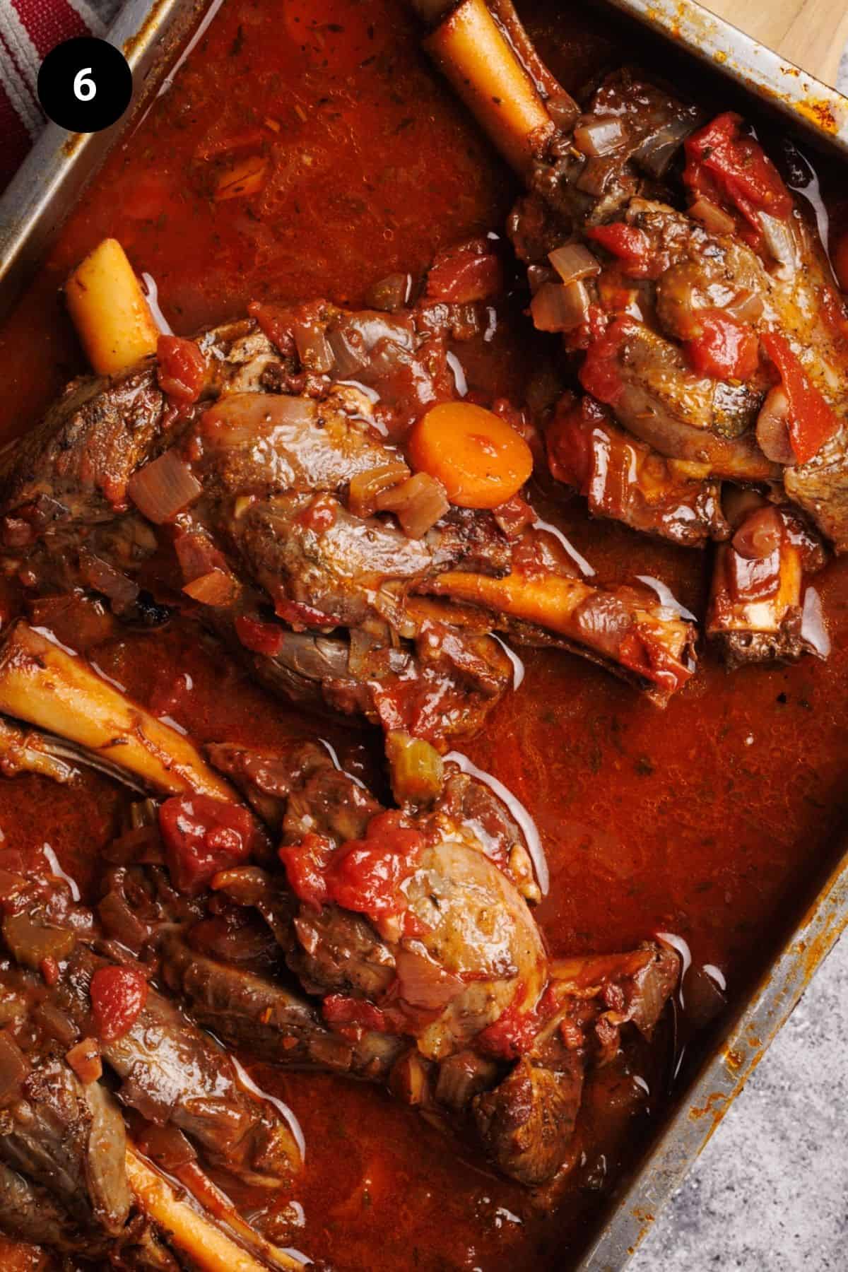 Cooked lamb shanks in a casserole dish.