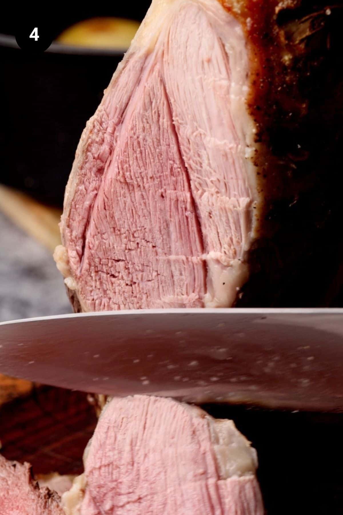 Pink lamb leg being carved after resting.