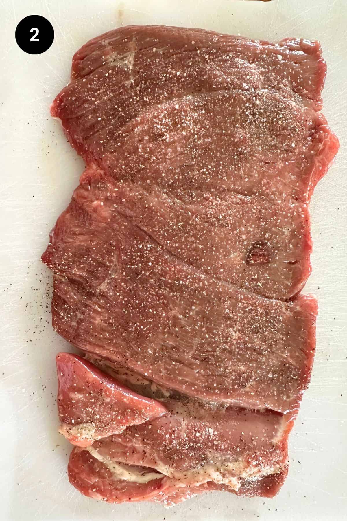 Boneless butterflied lamb leg on a white board.